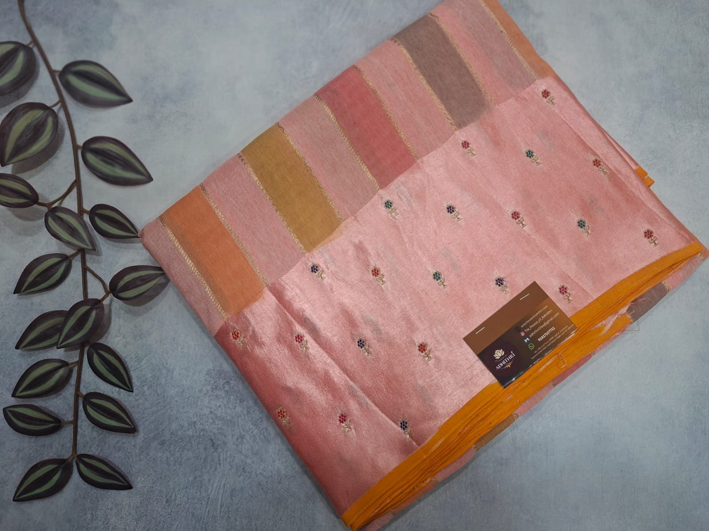 Pink and orange patterned fabric with a brand label on a gray surface.