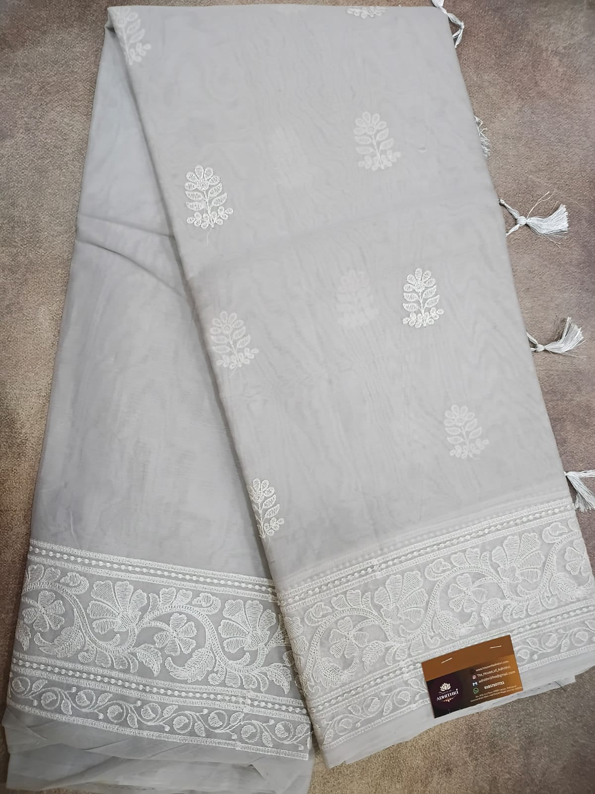 Gray fabric with white floral patterns and tassels on a brown surface