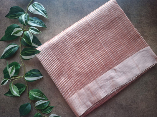 Folded pink fabric on a gray surface with green leaves in the corner