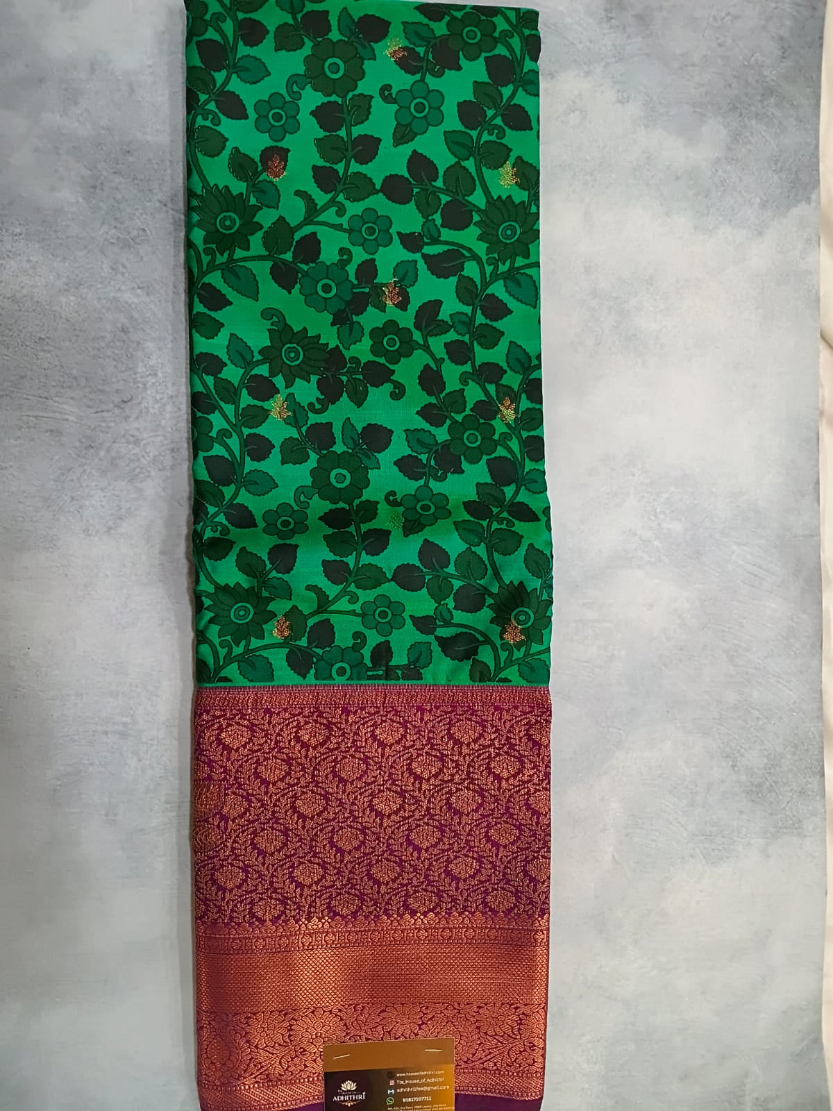 Folded fabric with green floral pattern, red and orange stripes on a gray background