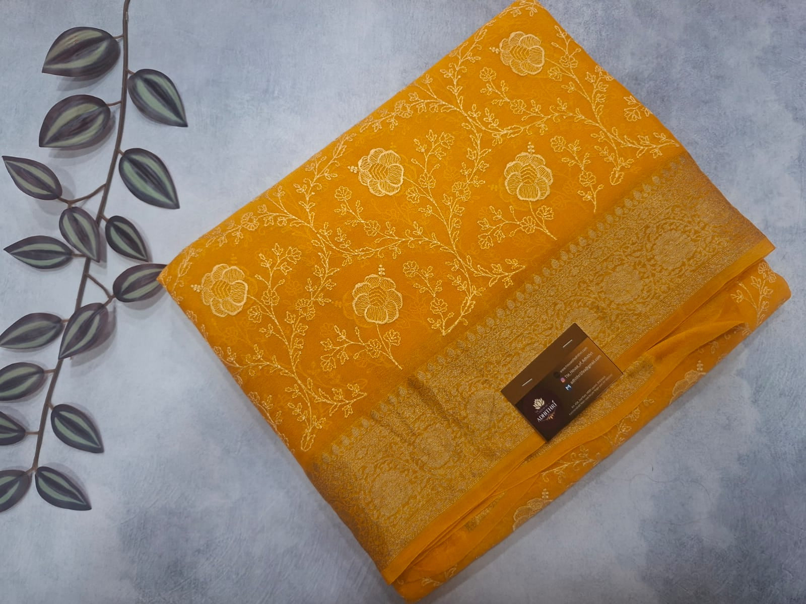 Yellow fabric with floral patterns on a gray surface with leaves.