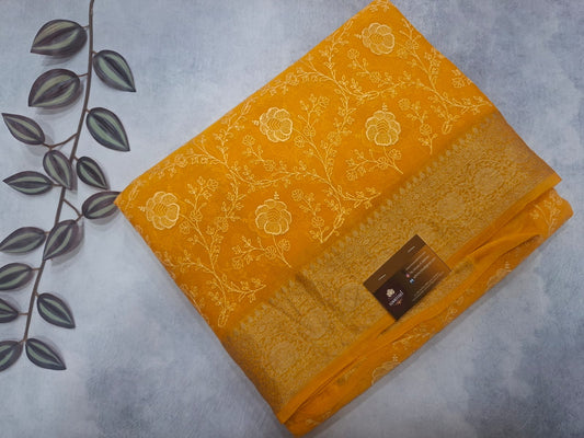 Yellow fabric with floral patterns on a gray surface with leaves.