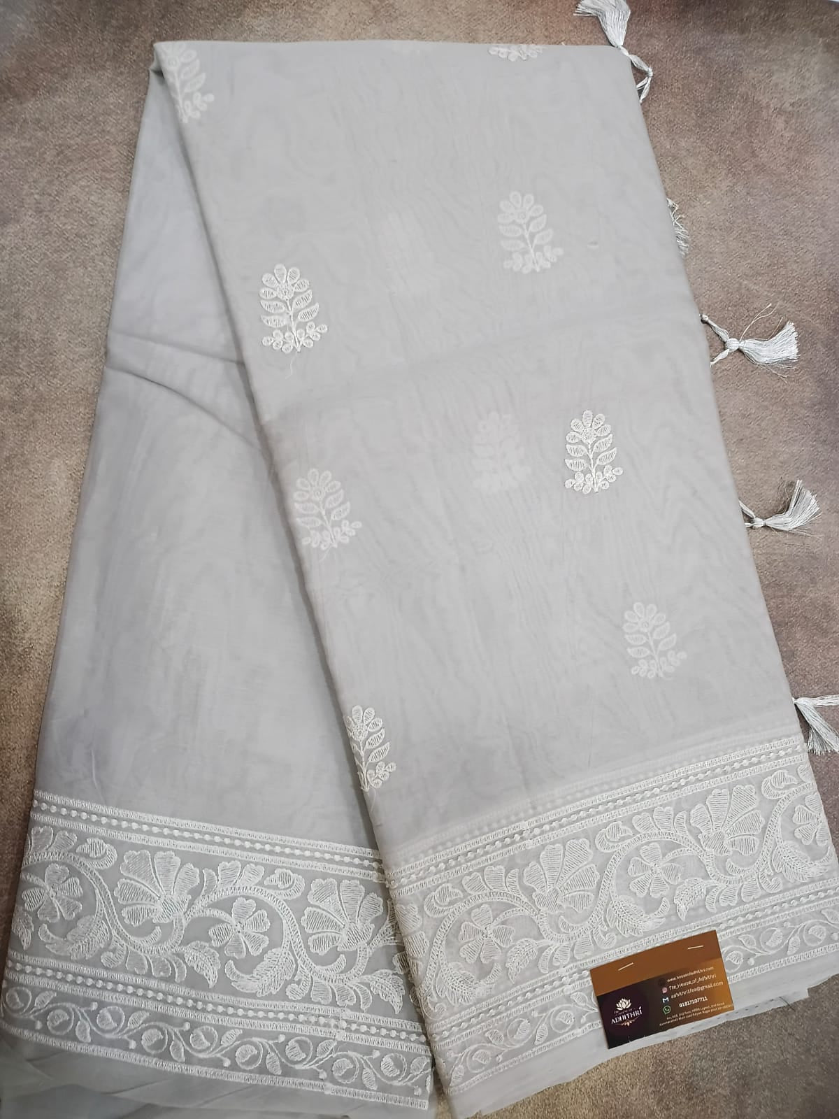 Gray fabric with white floral patterns and tassels on a brown surface