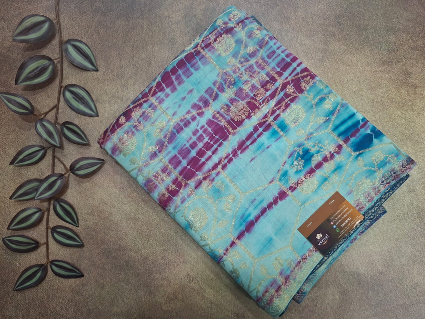 Colorful patterned fabric on a textured surface with a leaf decoration.