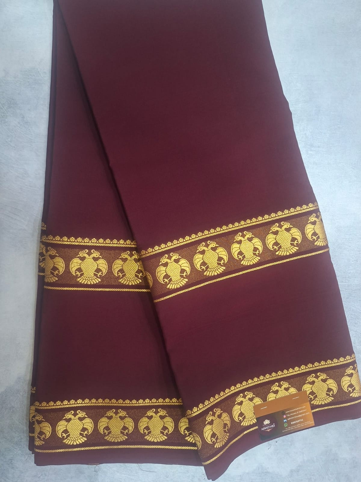 Maroon fabric with gold embroidery on a light gray background
