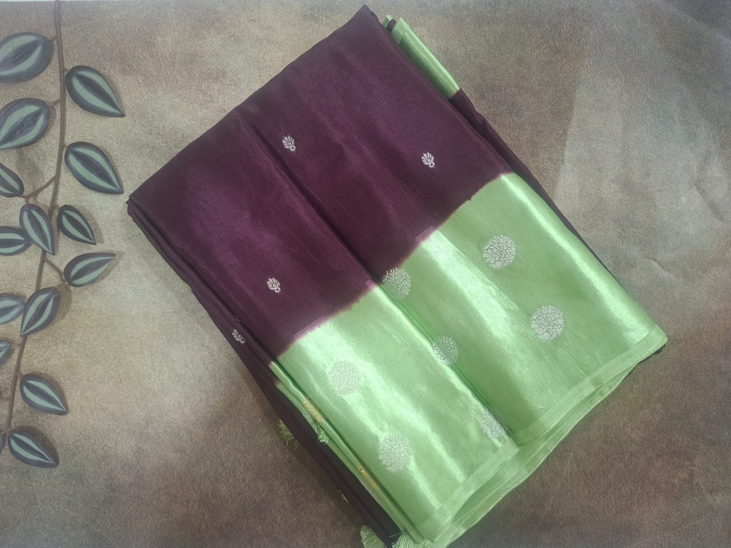 Green and maroon saree with white floral patterns on a textured surface