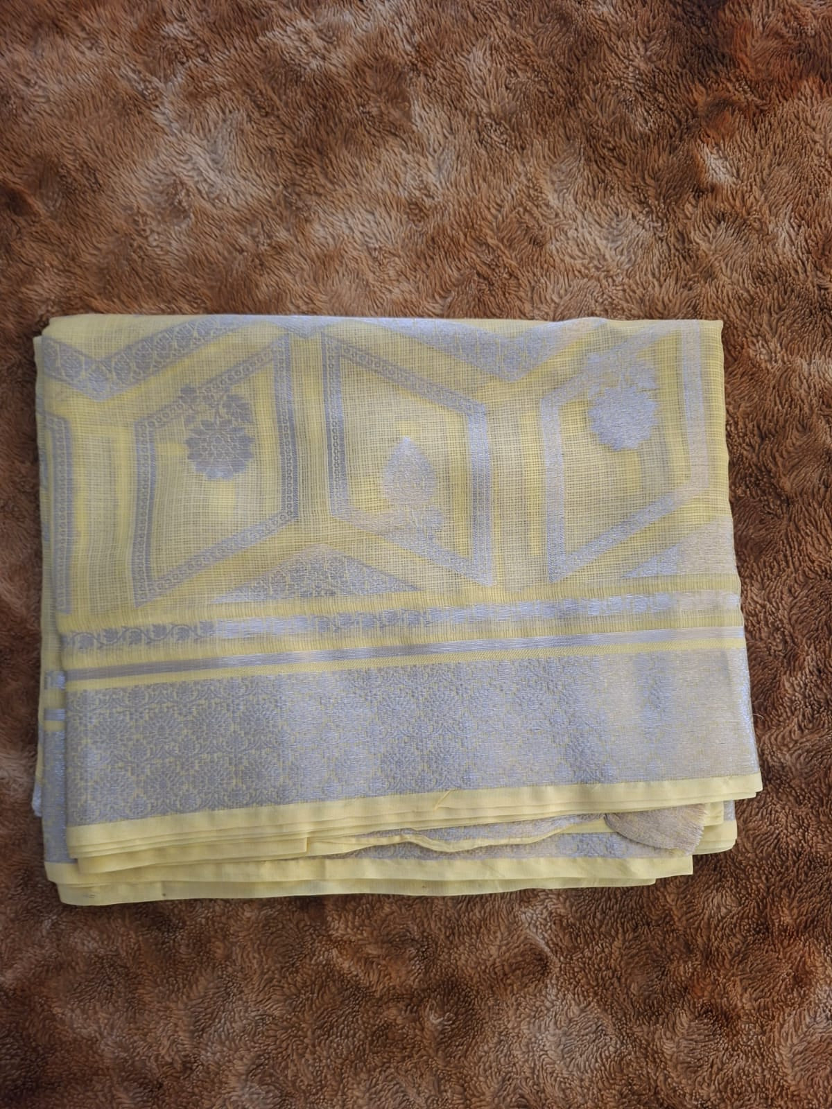 Folded yellow and gray patterned towel on a brown textured surface