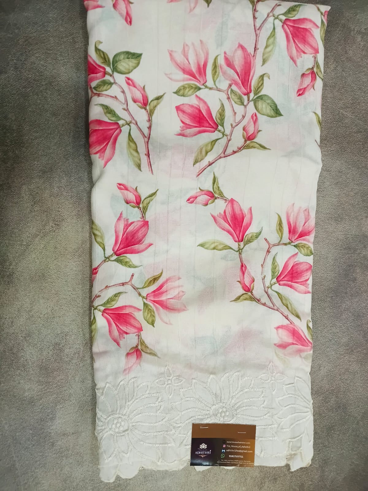 Floral-patterned fabric with pink flowers on a white background, lying flat on a gray surface.