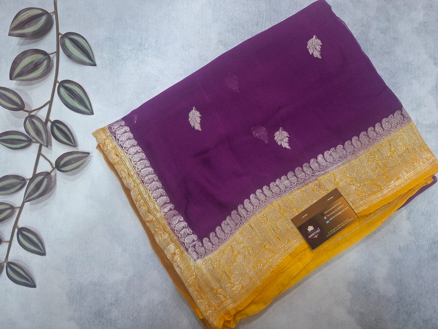 Purple and yellow saree with leaf patterns on a light gray background