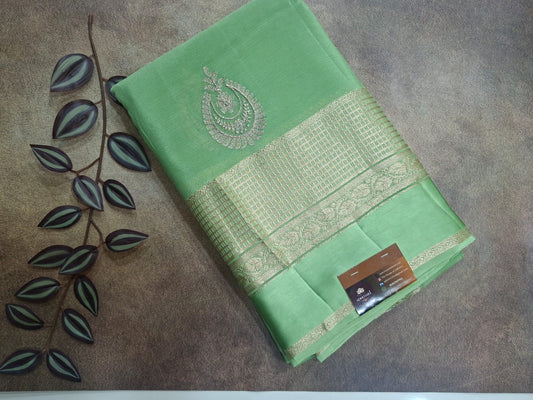 Green saree with gold border on a textured surface