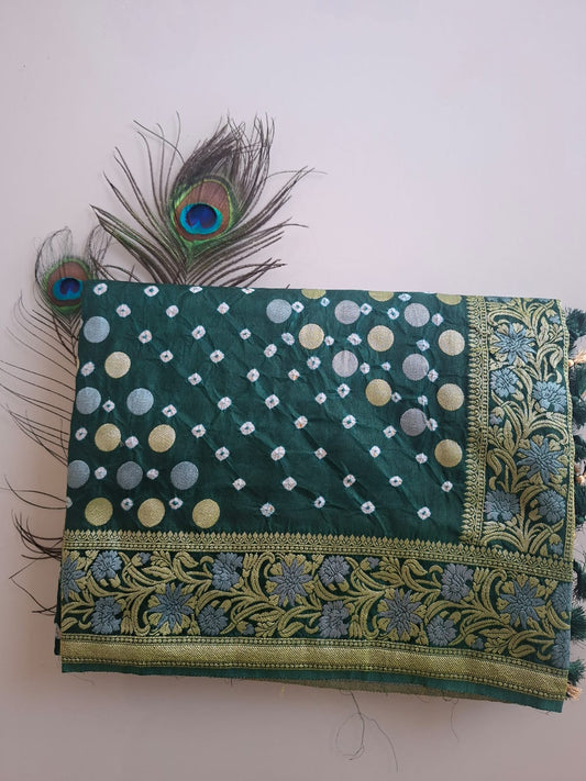 Green embroidered fabric with peacock feathers on a light pink background