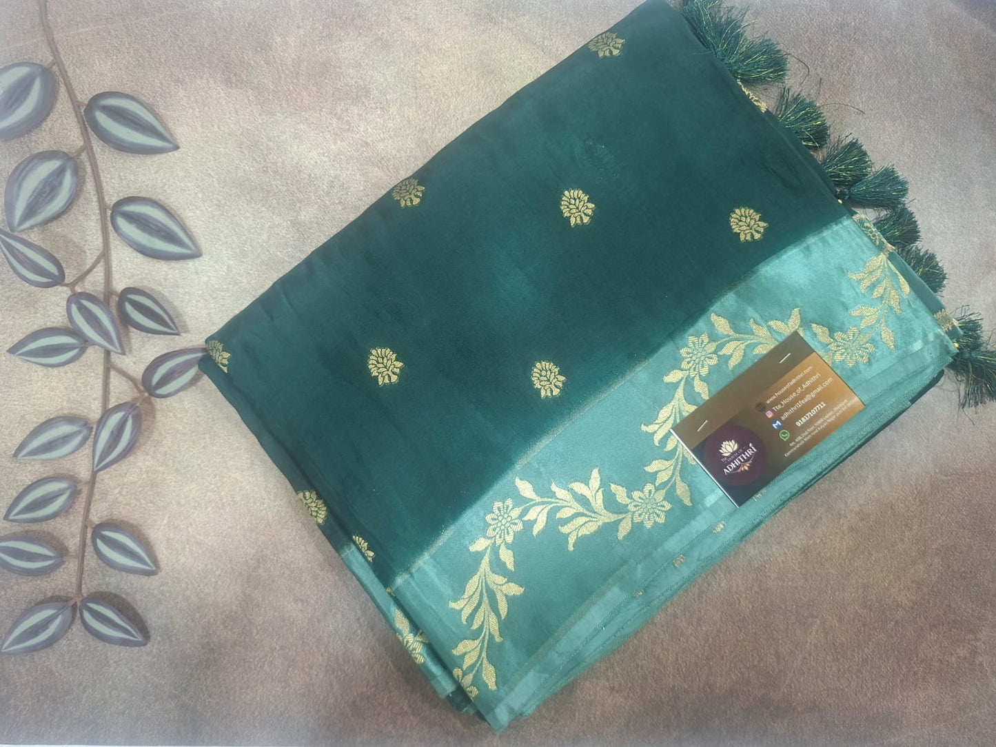 Green saree with gold patterns on a beige surface