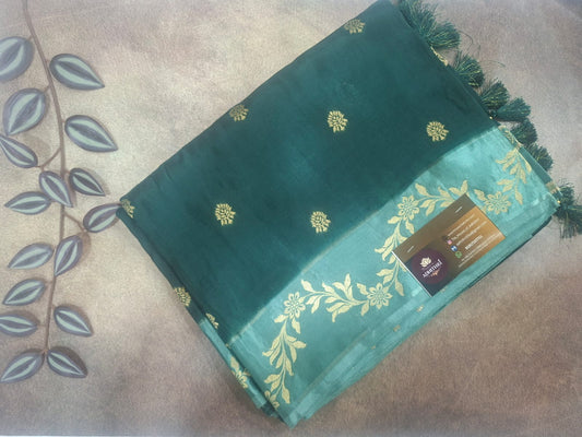 Green saree with gold patterns on a beige surface