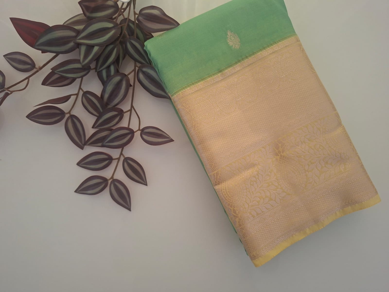 Beige and green fabric with leaf design on a plain background