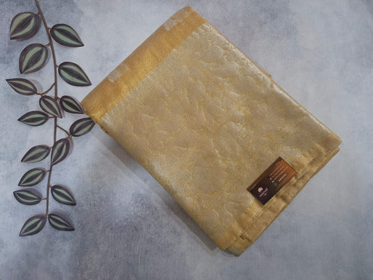 Beige textured fabric on a gray surface with a decorative leaf design.