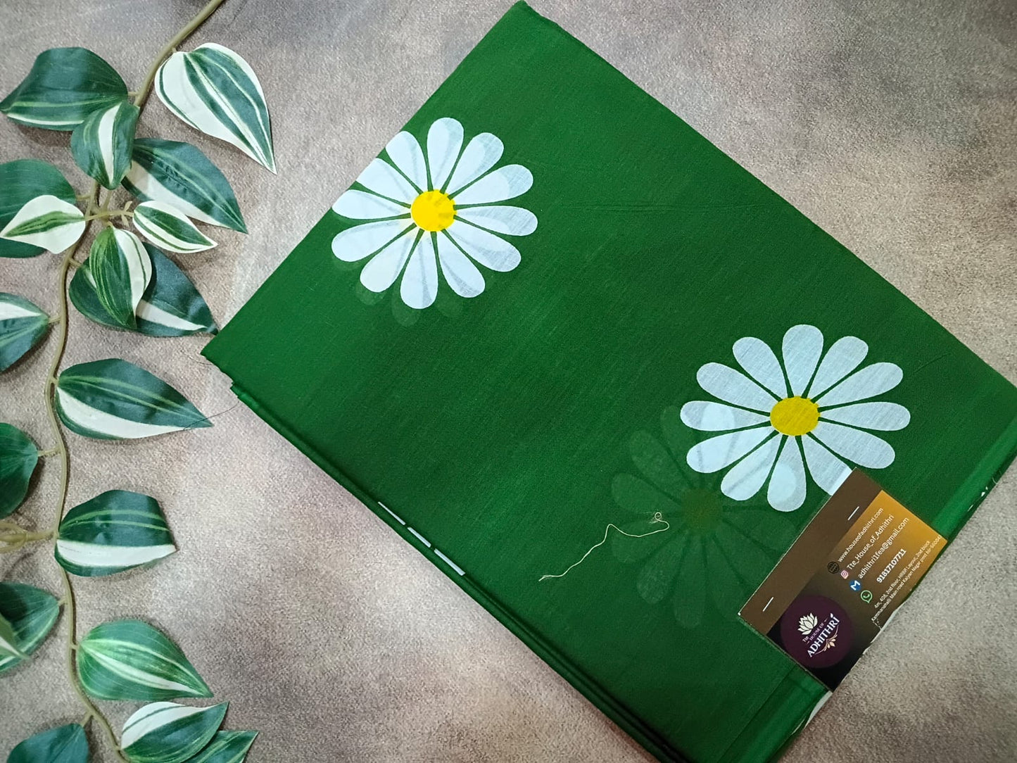 Green mat with white daisy designs on a textured surface with leaves.