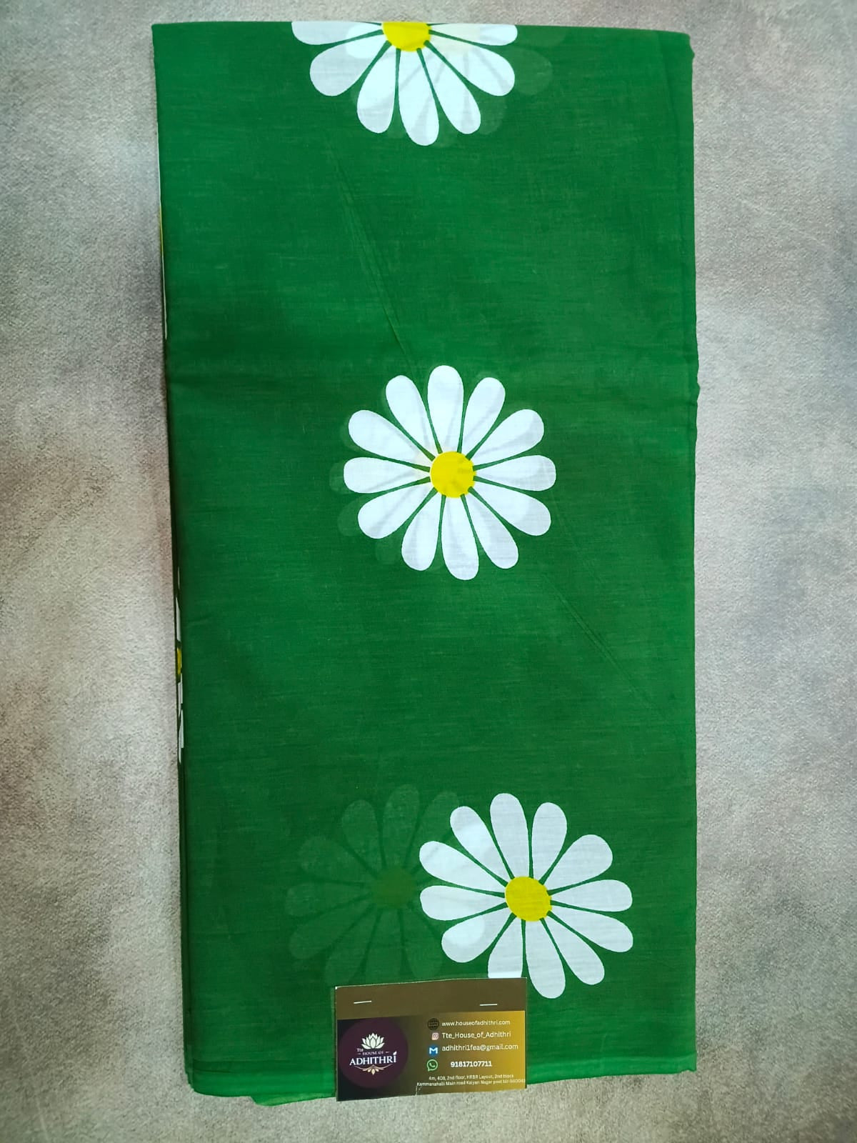 Green fabric with white daisy flowers on a gray surface