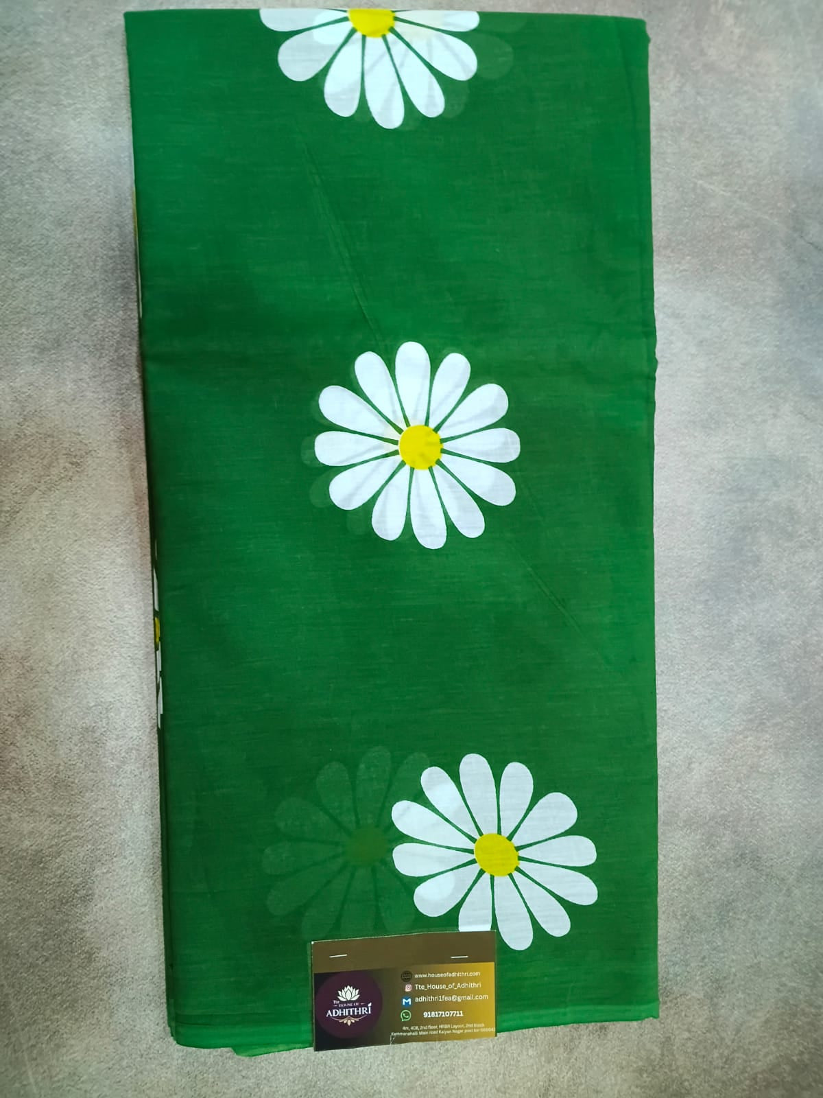 Green fabric with white daisy flowers on a gray surface