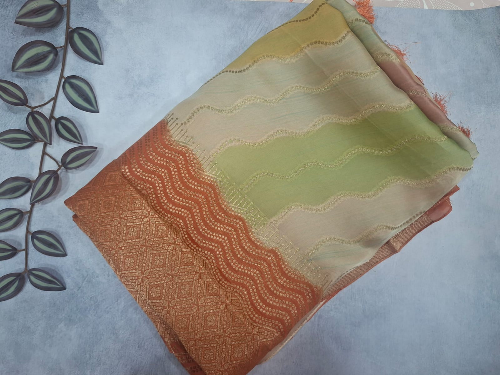 Folded fabric with orange and green patterns on a light gray background