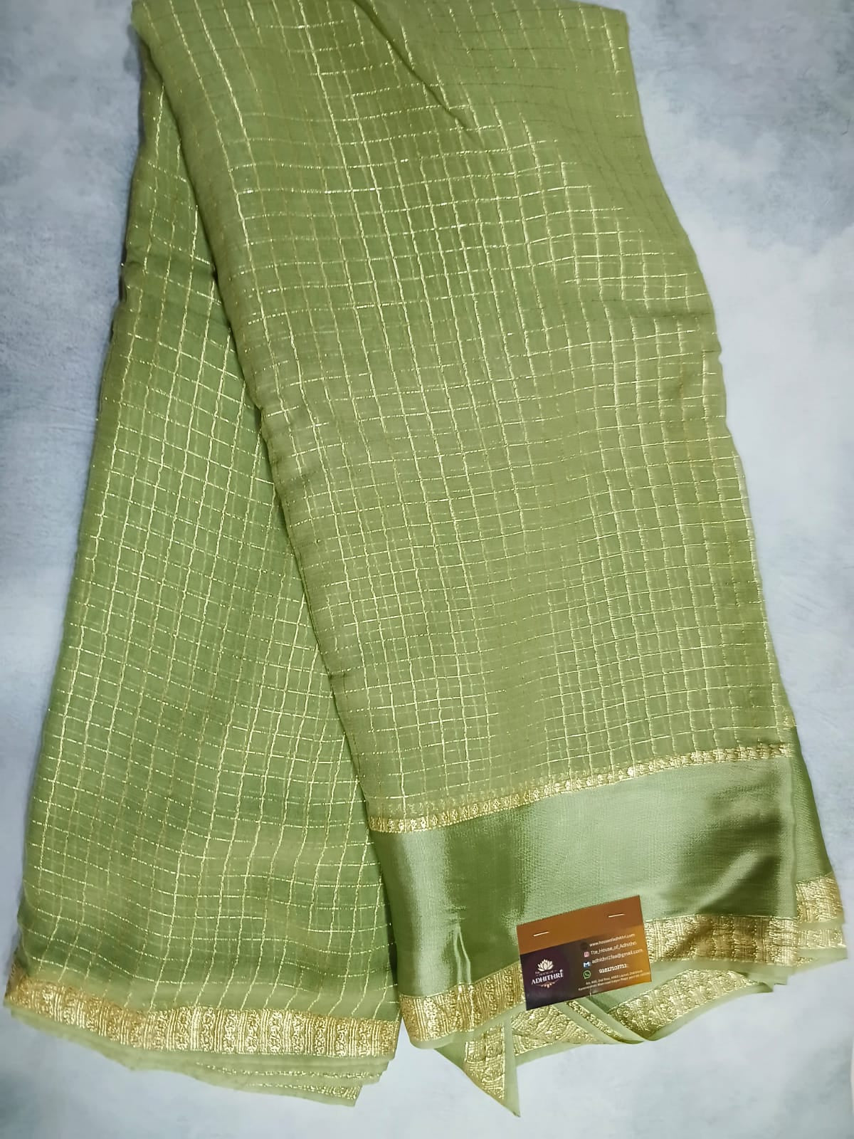 Green fabric with gold border and label on a light gray background