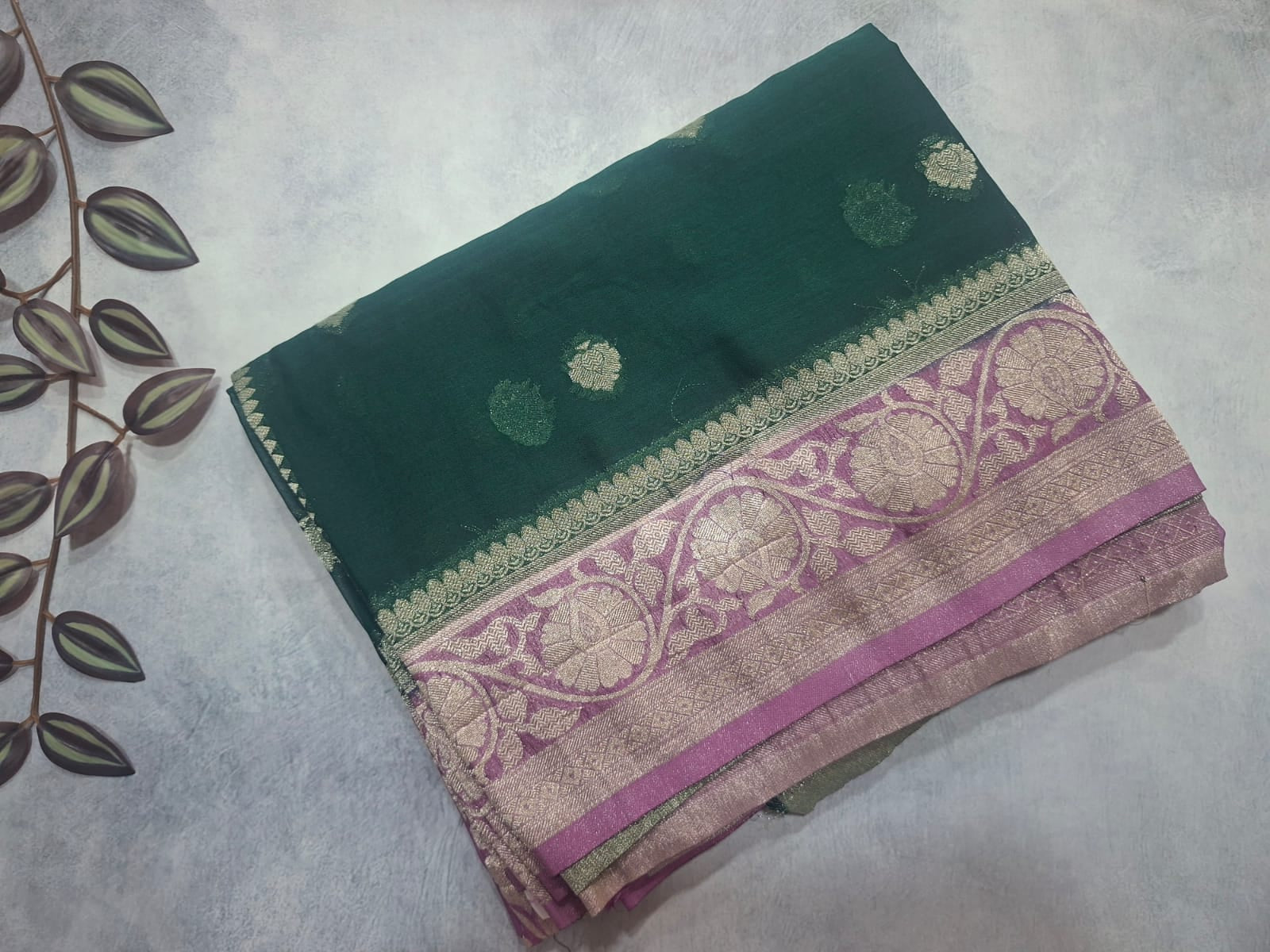 Green and pink saree with intricate patterns on a light gray background