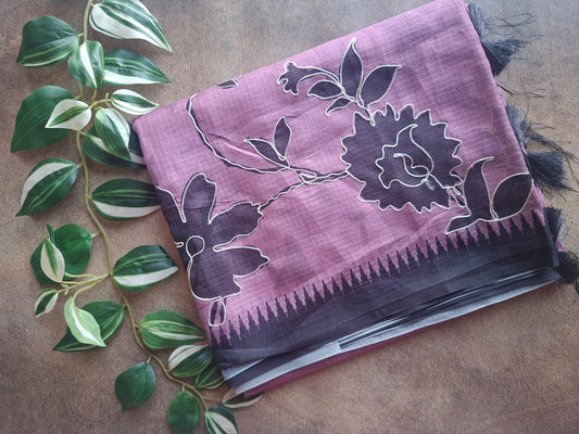 Purple fabric with floral patterns on a wooden surface with green leaves.