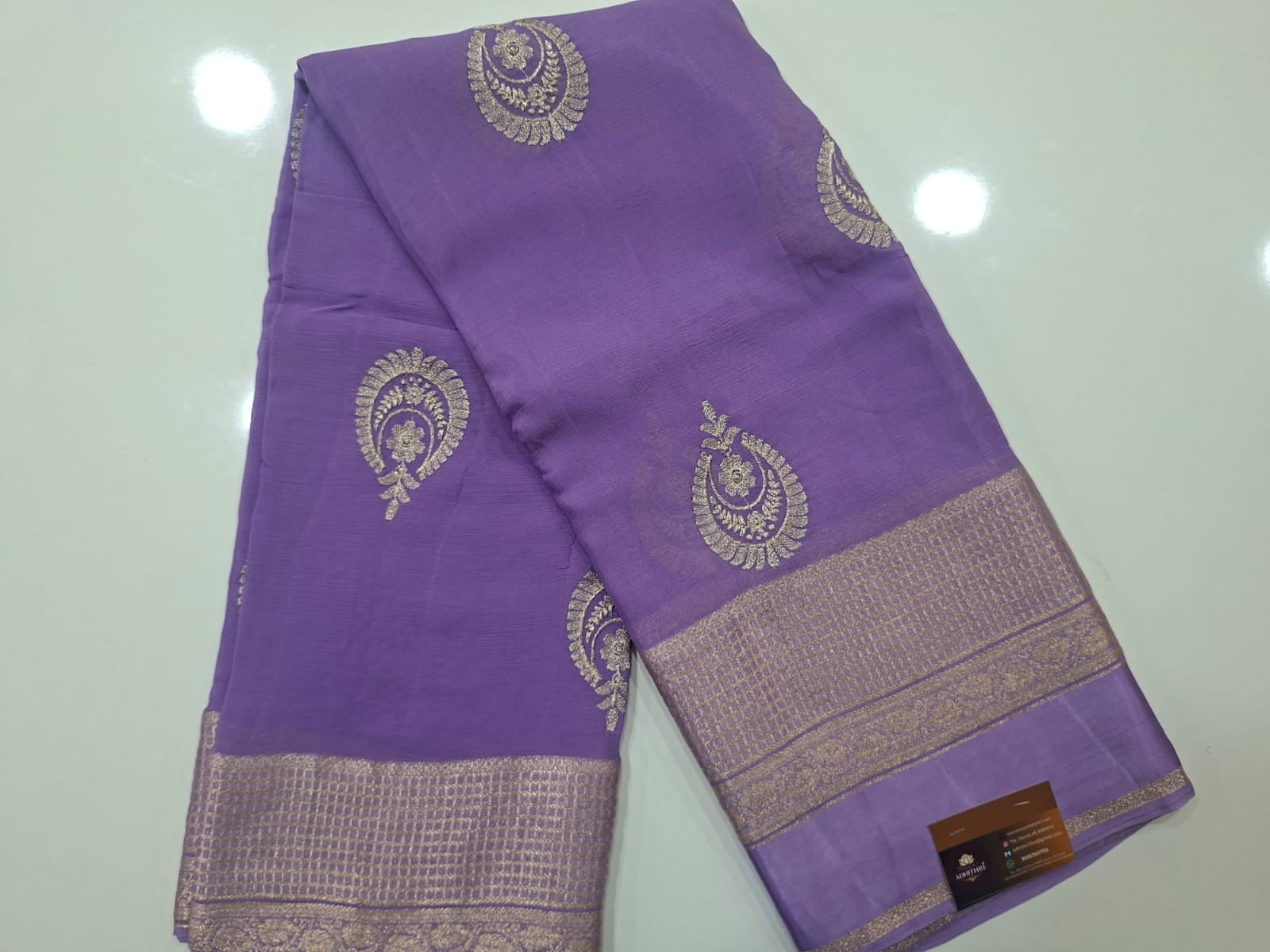 Purple saree with gold patterns on a light gray background