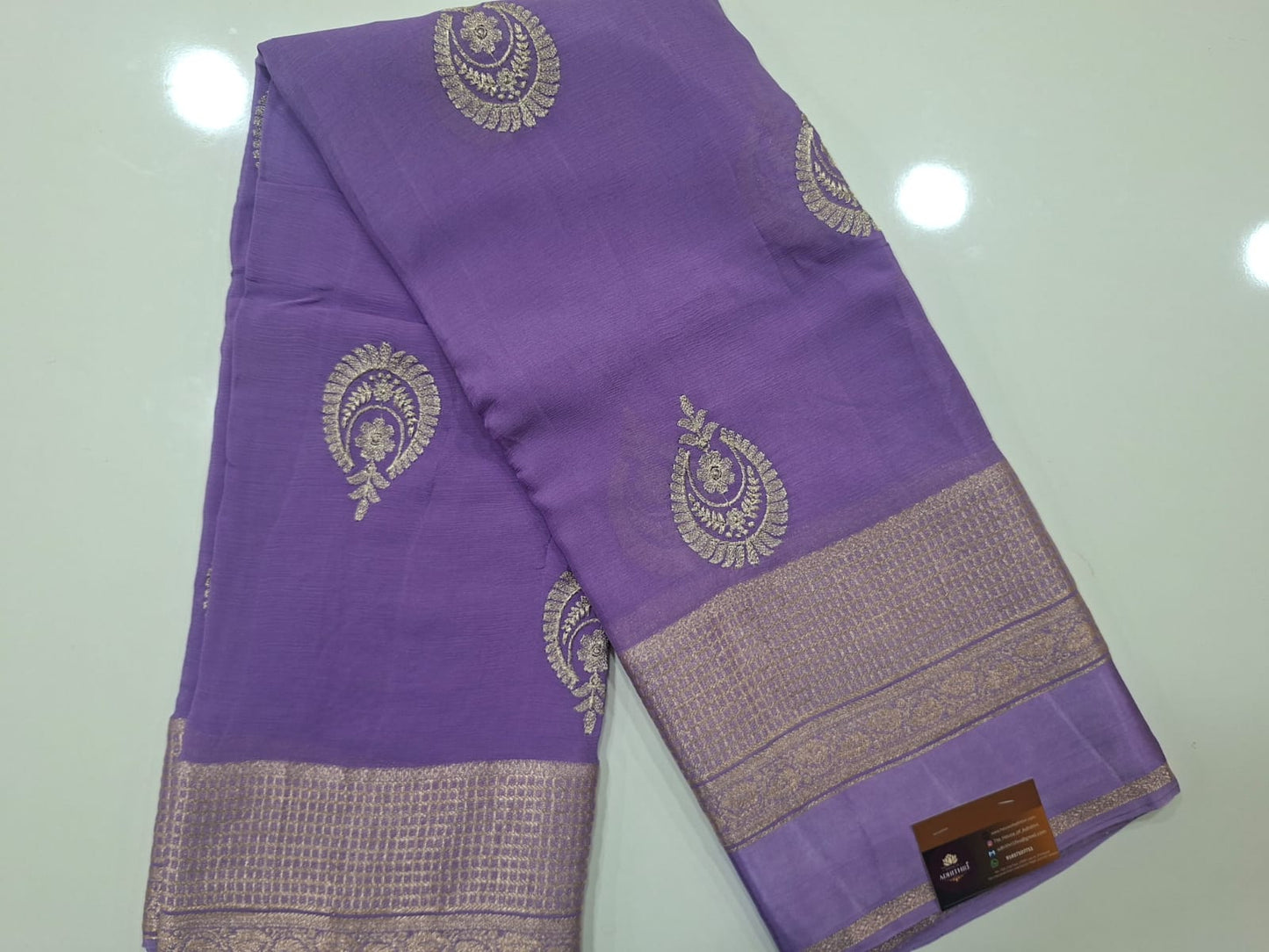 Purple saree with gold patterns on a light gray background
