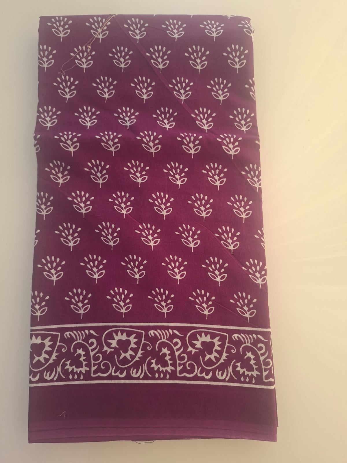 Purple fabric with white floral pattern on a beige background