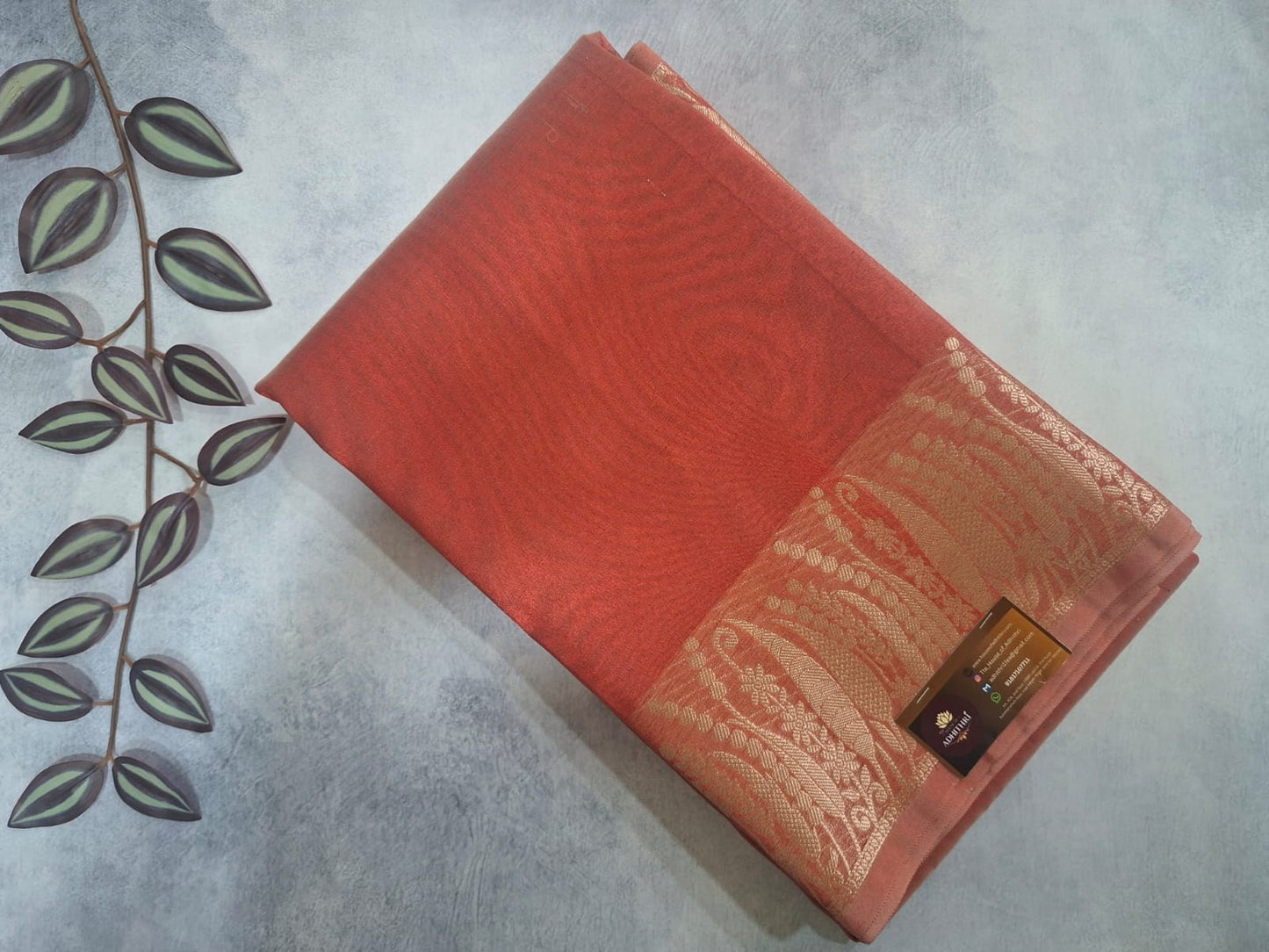 Red book with decorative cover on a gray surface with a plant leaf decoration.