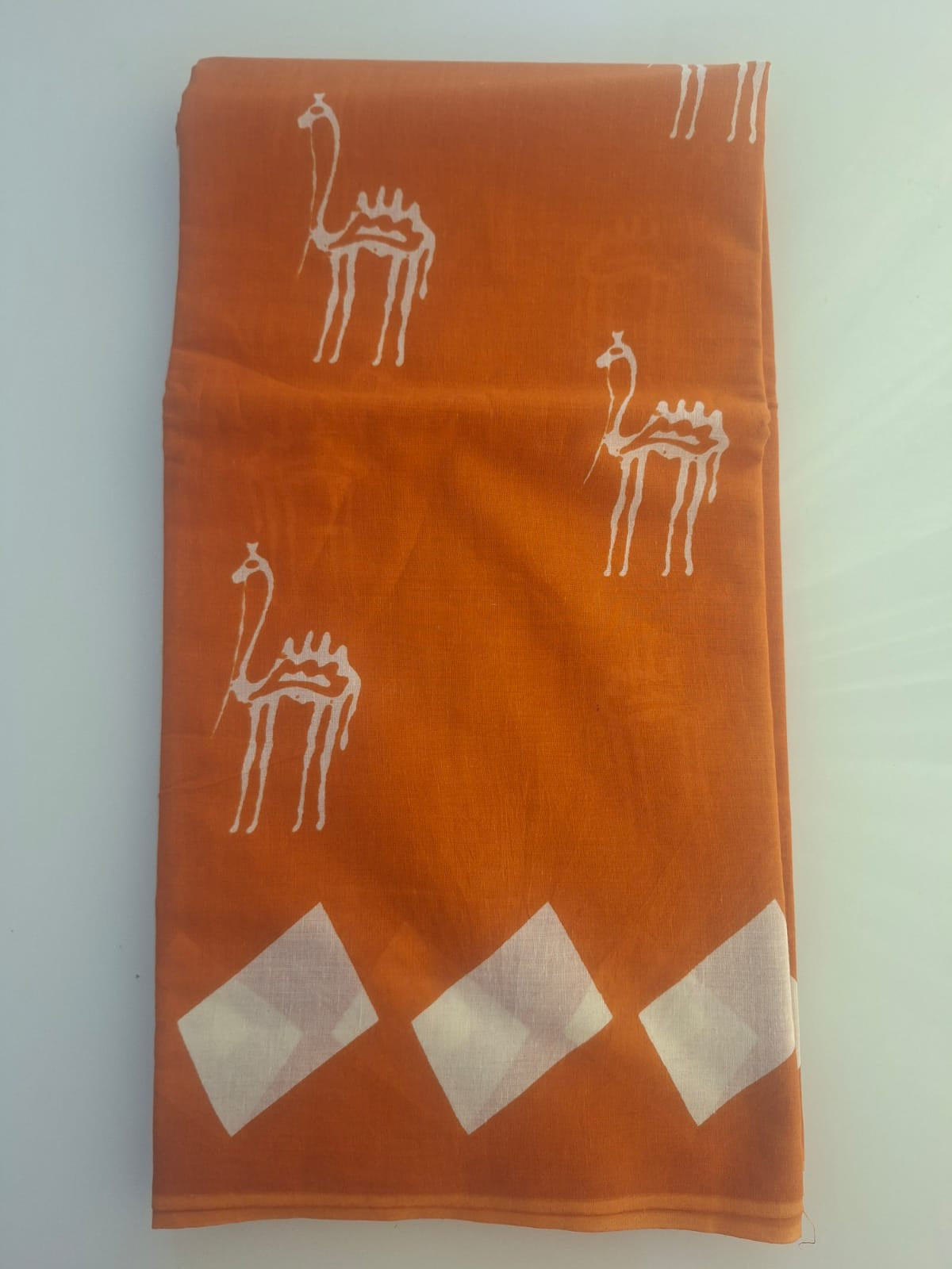 Orange fabric with white patterns on a light gray background