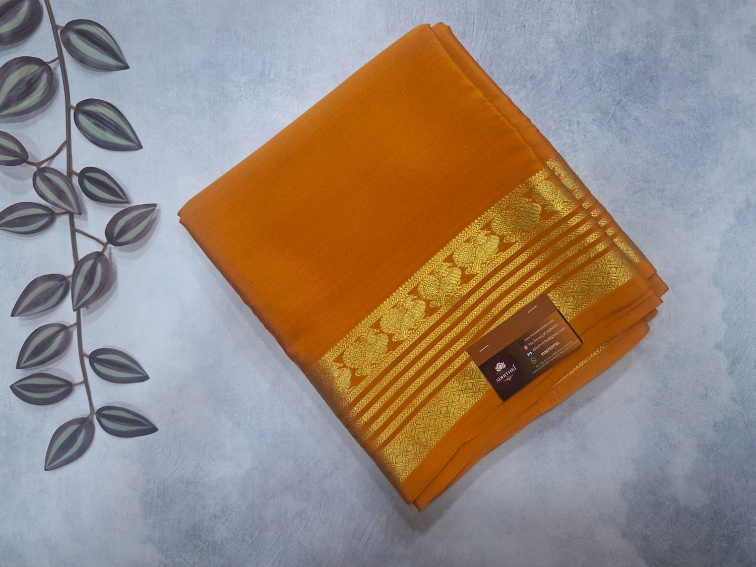 Orange saree with gold border on a light gray background