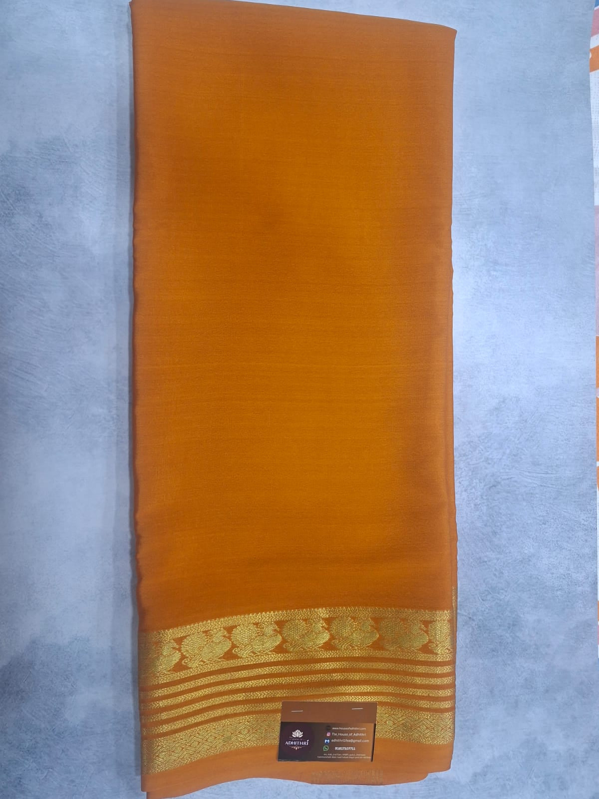 Brown saree with gold border on a light gray background