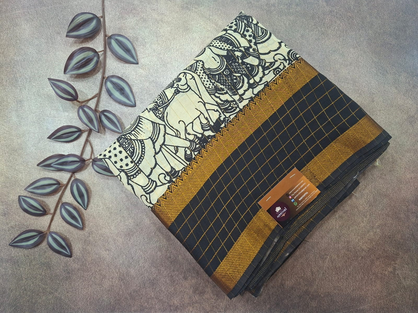 Folded fabric with elephant design and grid pattern on a textured surface with leaves.