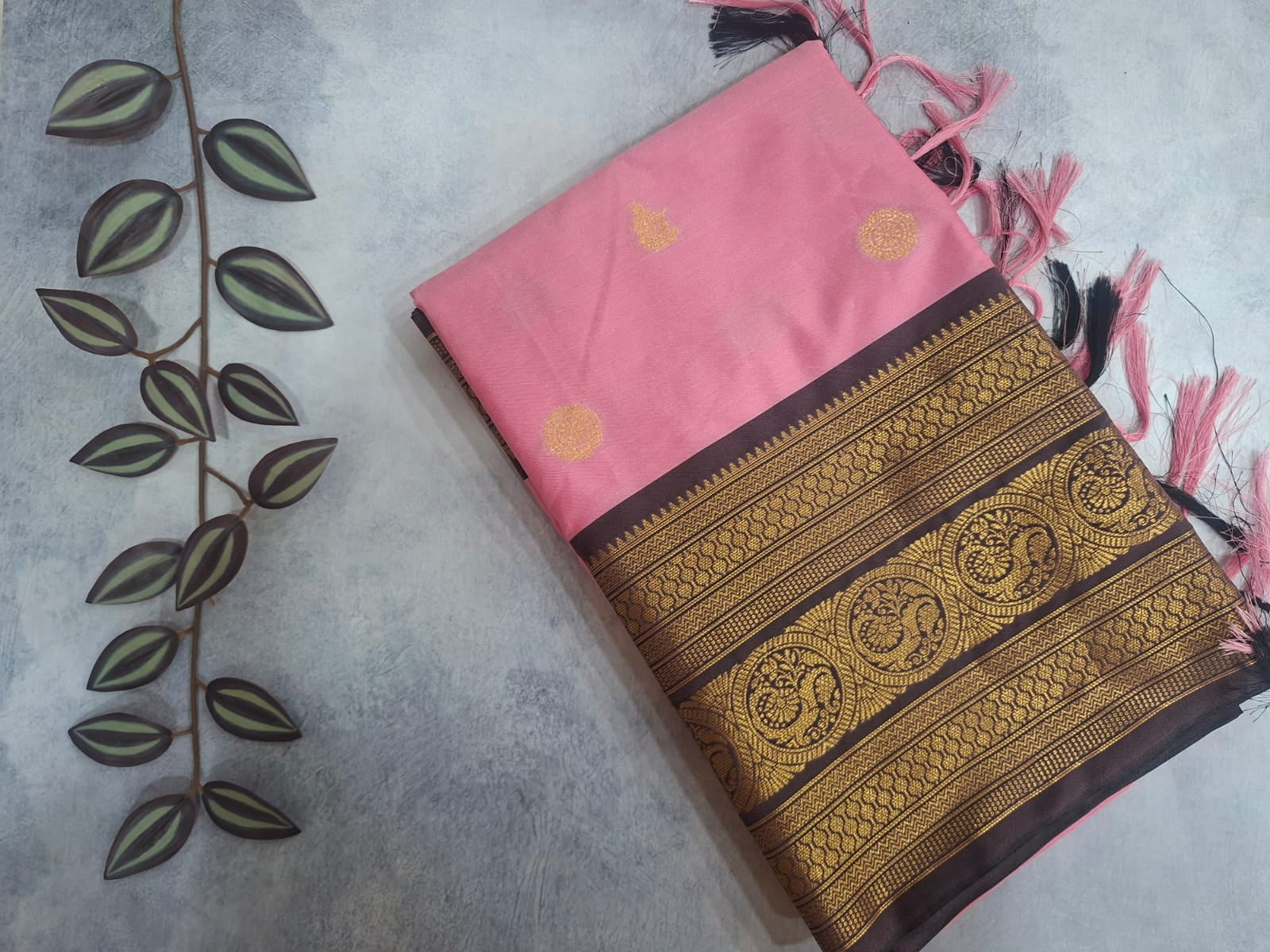 Two traditional sarees with intricate patterns on a textured surface.