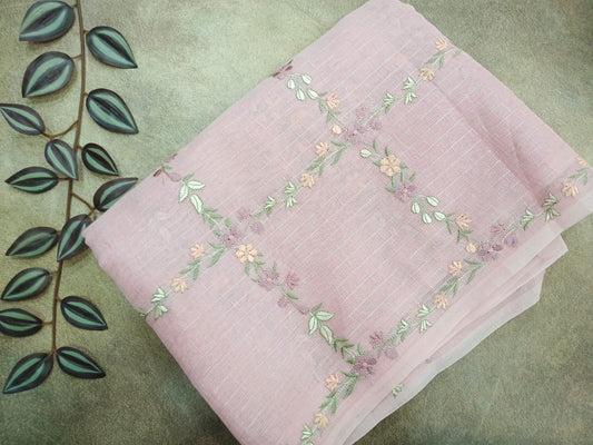 Pink fabric with floral embroidery on a green leafy background