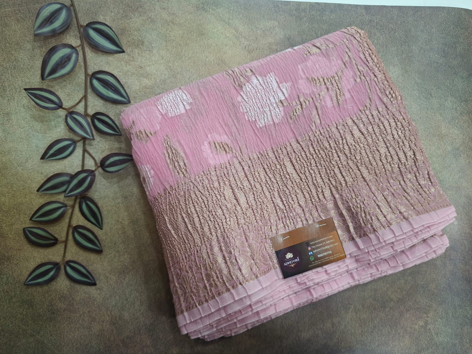 Folded pink towel with a brand label on a textured surface