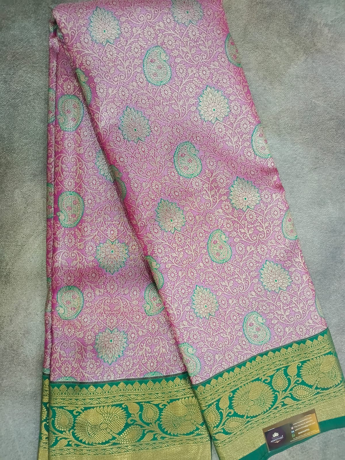 Pink saree with green border on a gray surface