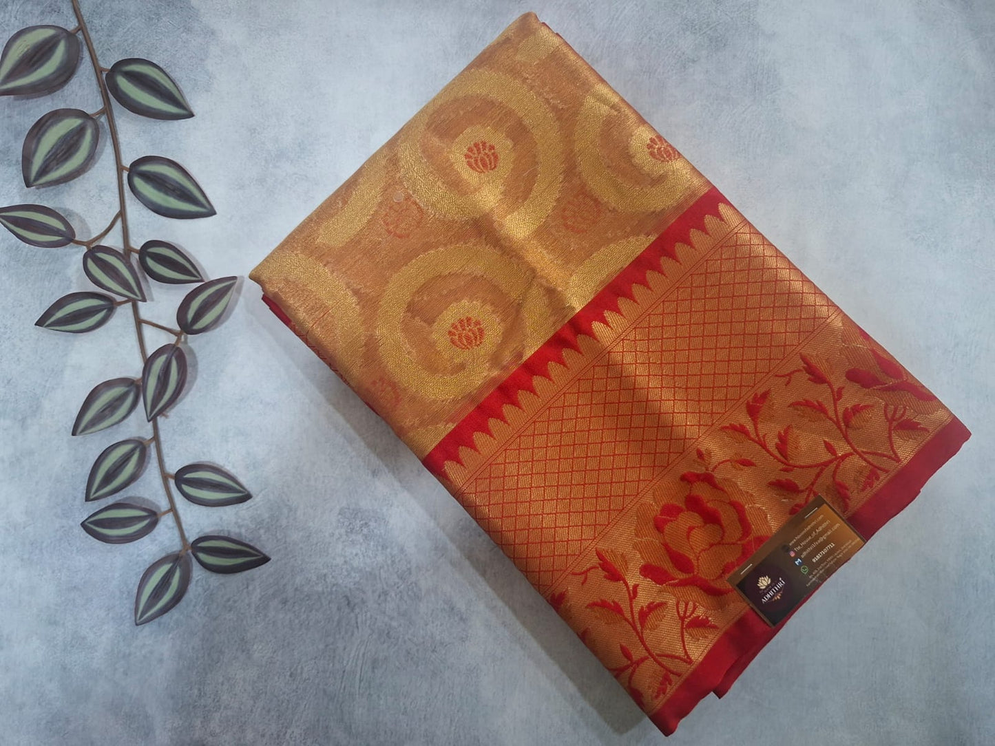 Orange and red patterned fabric on a textured surface with a plant leaf decoration.