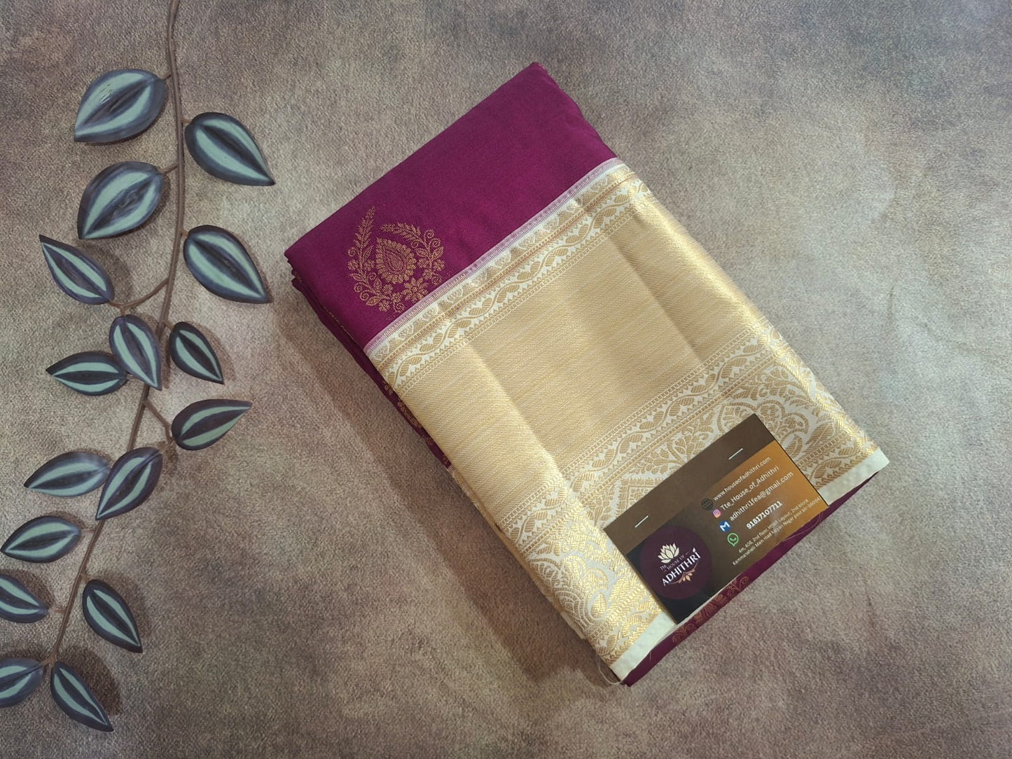 Saree with a purple border on a textured surface with leaf decorations