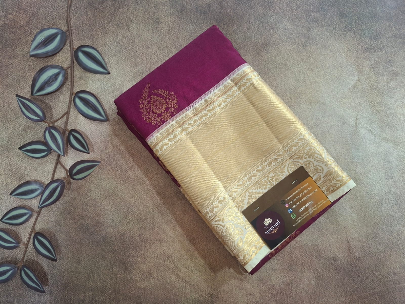 Saree with a purple border on a textured surface with leaf decorations