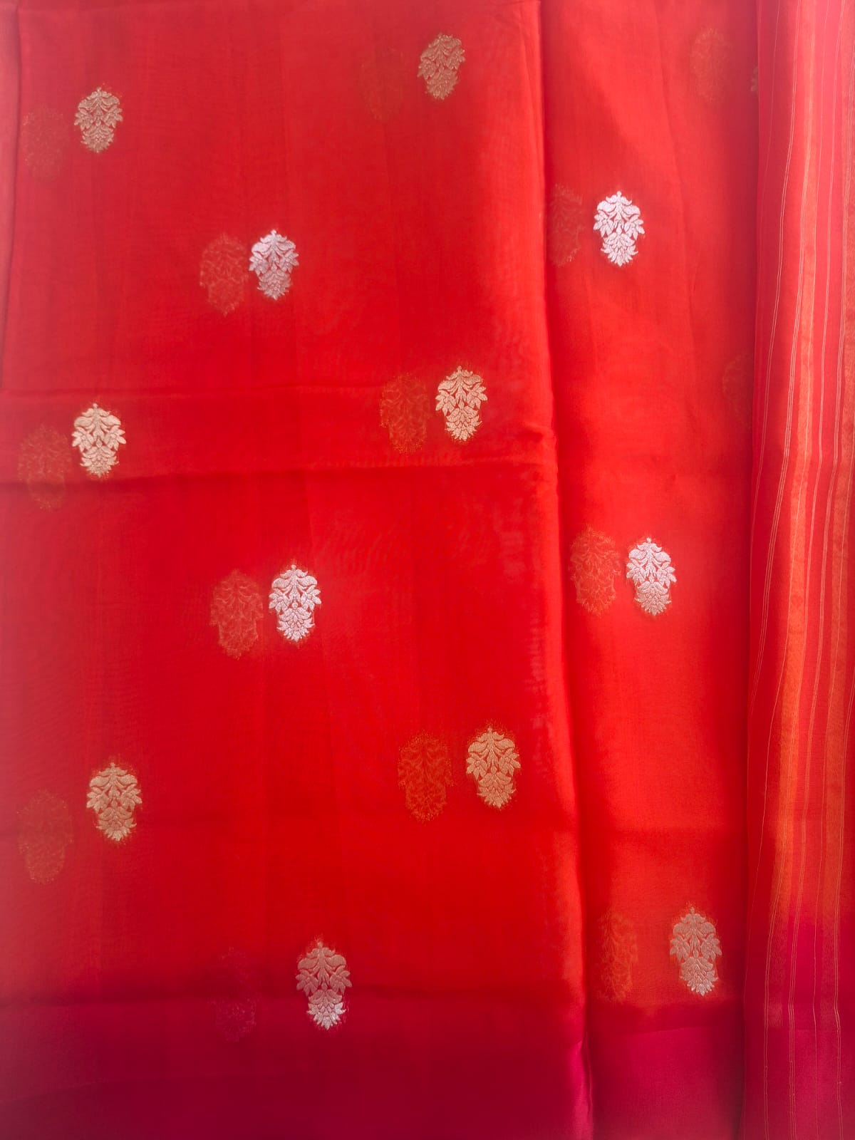 Red fabric with gold floral patterns on a plain background