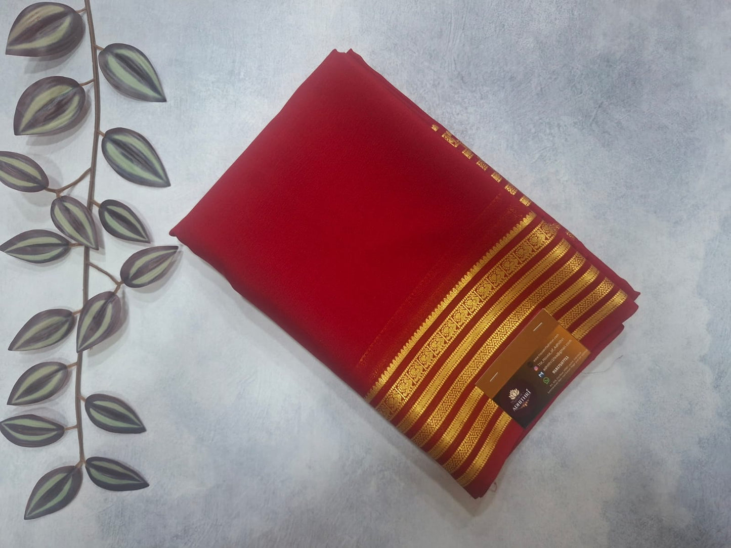 Red fabric with gold stripes on a light gray background with decorative leaves.