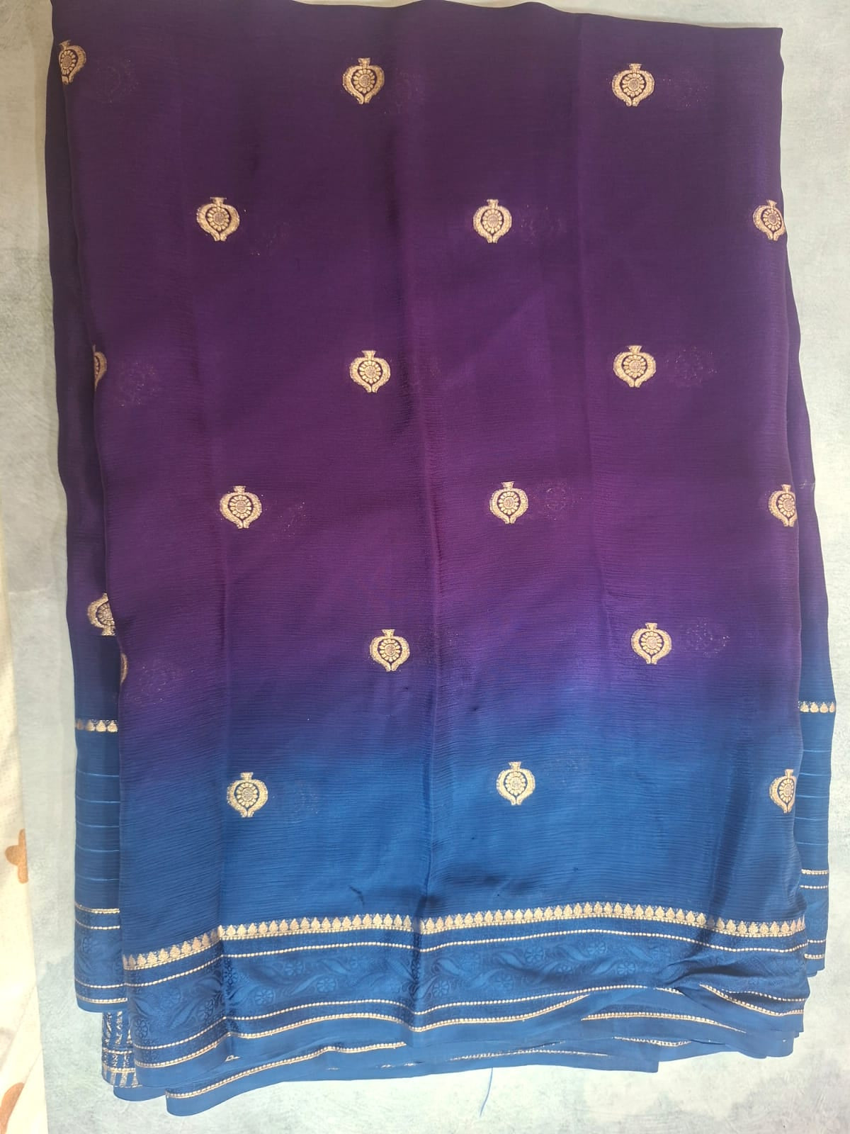 Blue and purple fabric with gold patterns on a light gray background