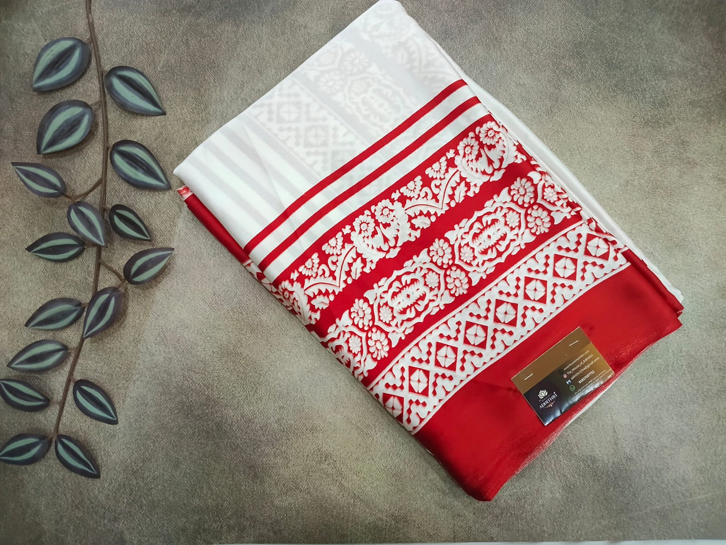 Red and white patterned fabric with a gold tag on a gray surface