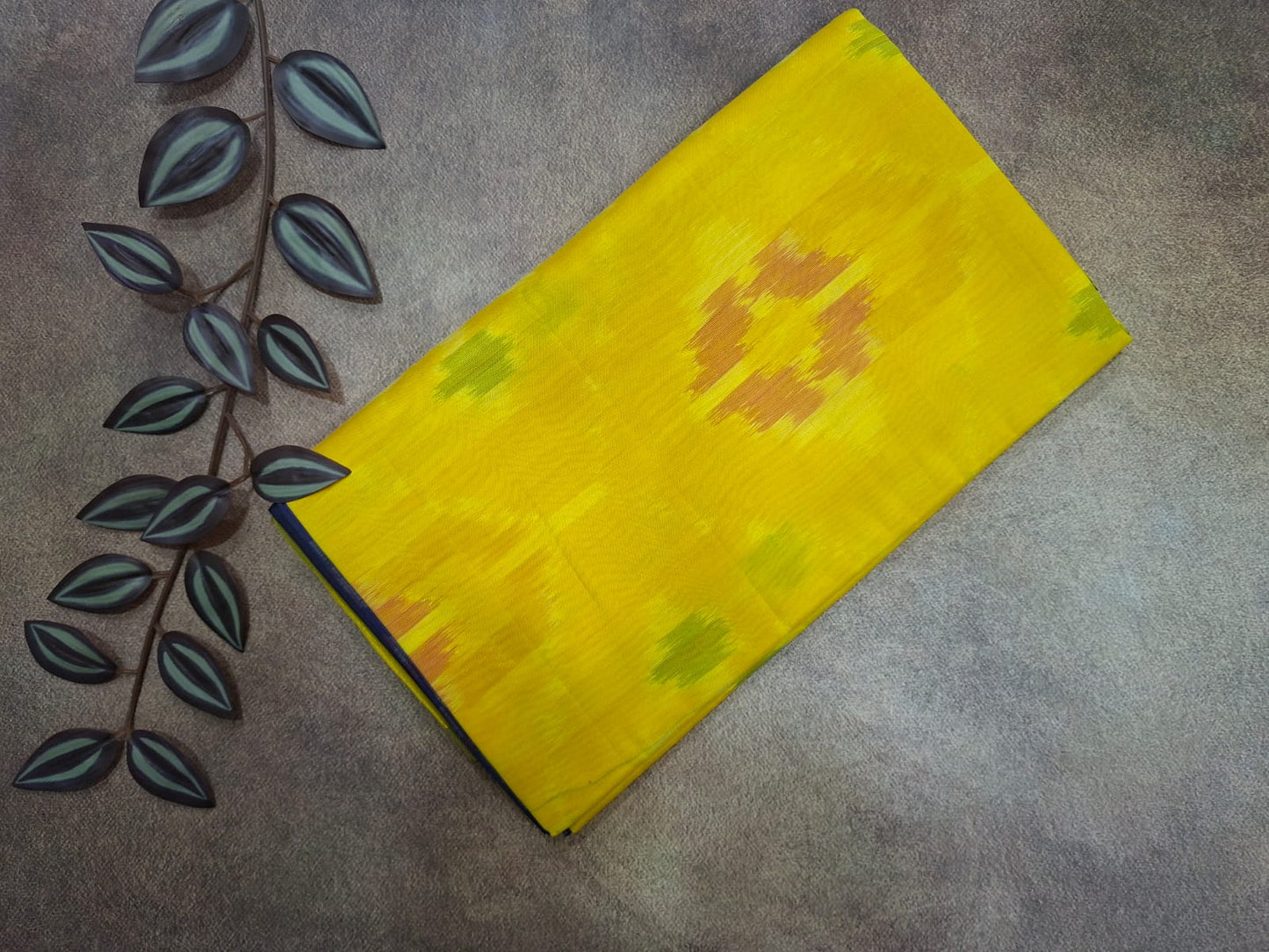 Yellow fabric with floral patterns on a gray surface with leaf decorations.