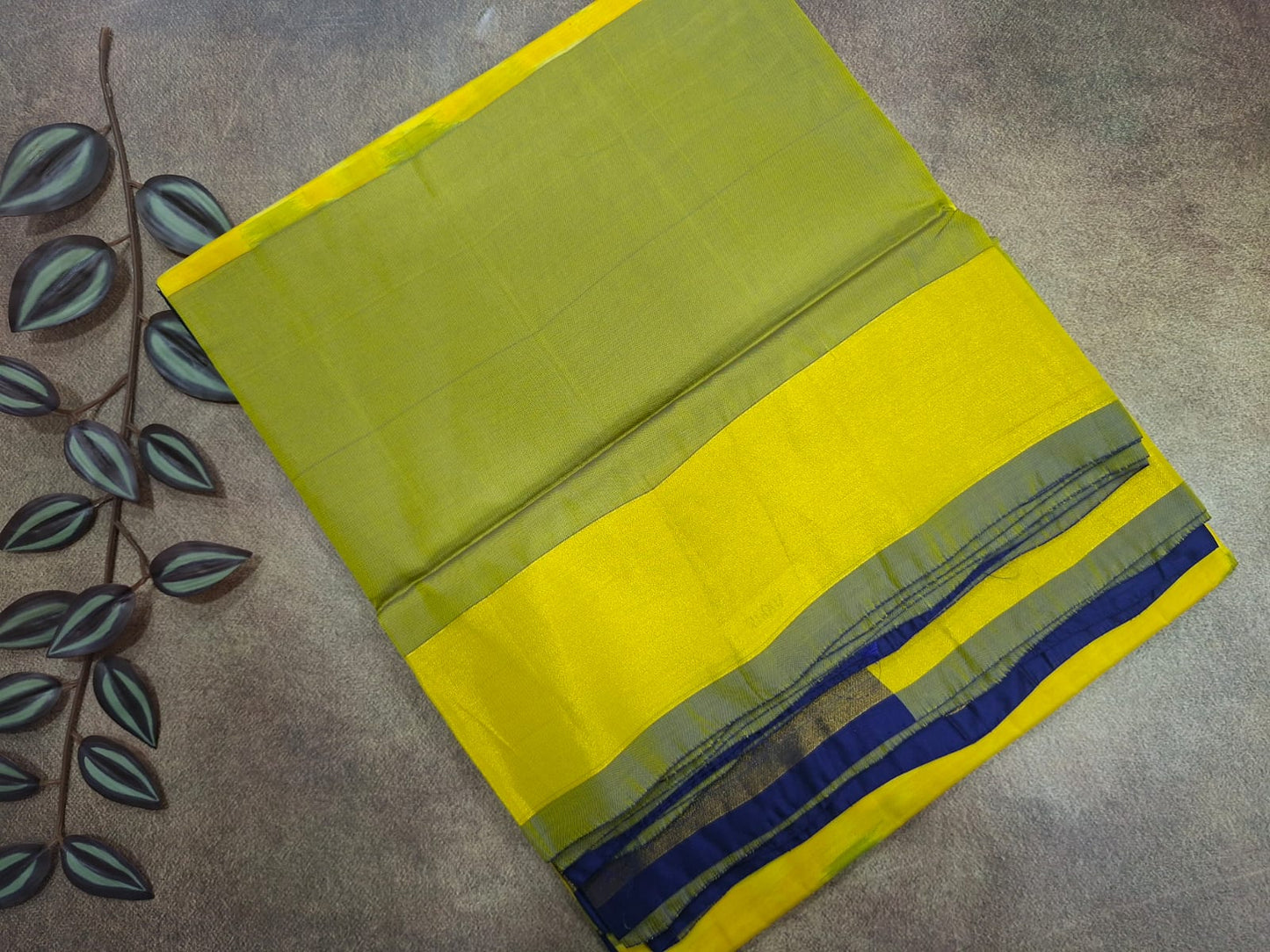 Green and yellow fabric with blue stripes on a textured surface